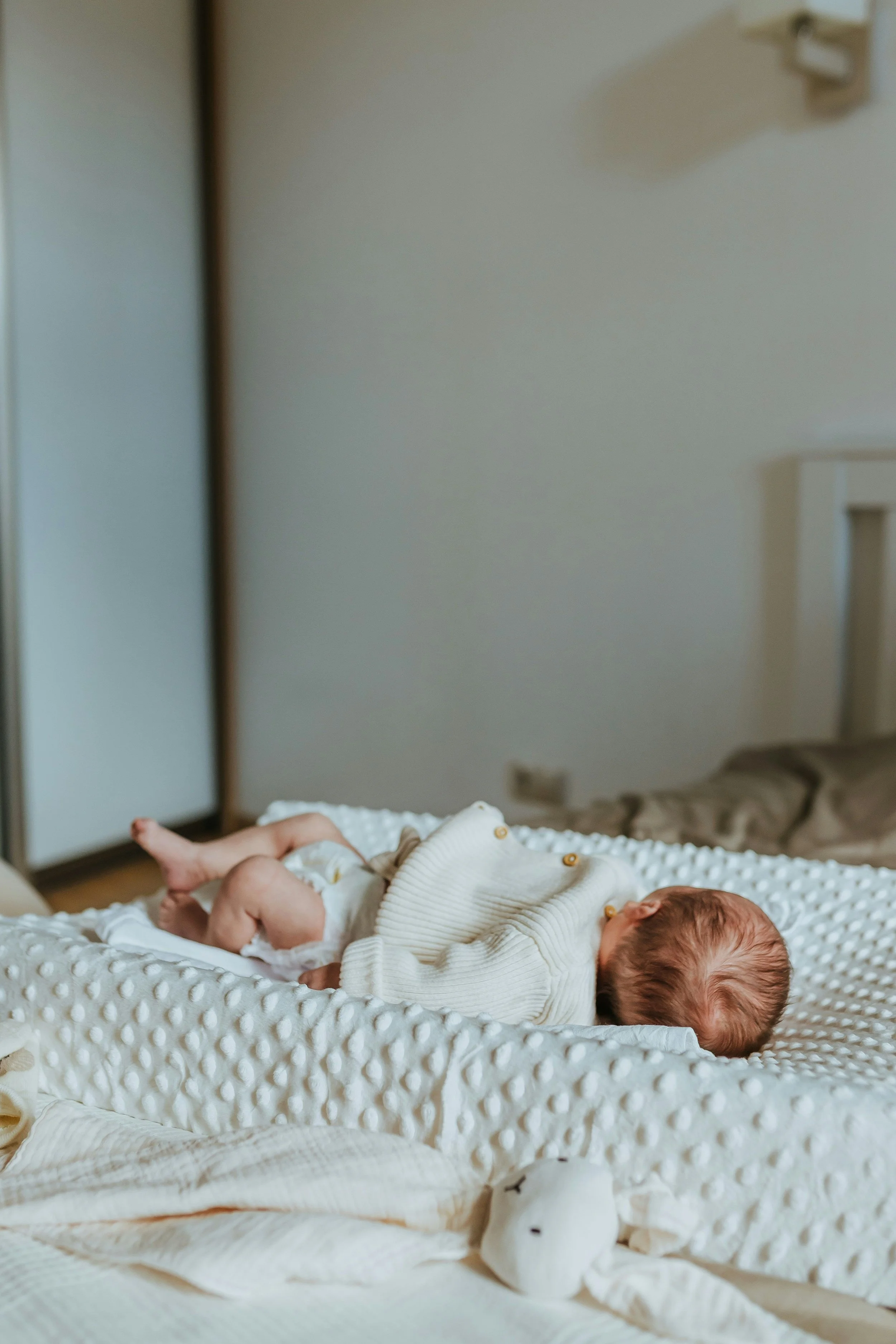 Awake and alert newborn baby on soft blanket, supported by Om Baby's newborn sleep consultation services in Los Angeles

