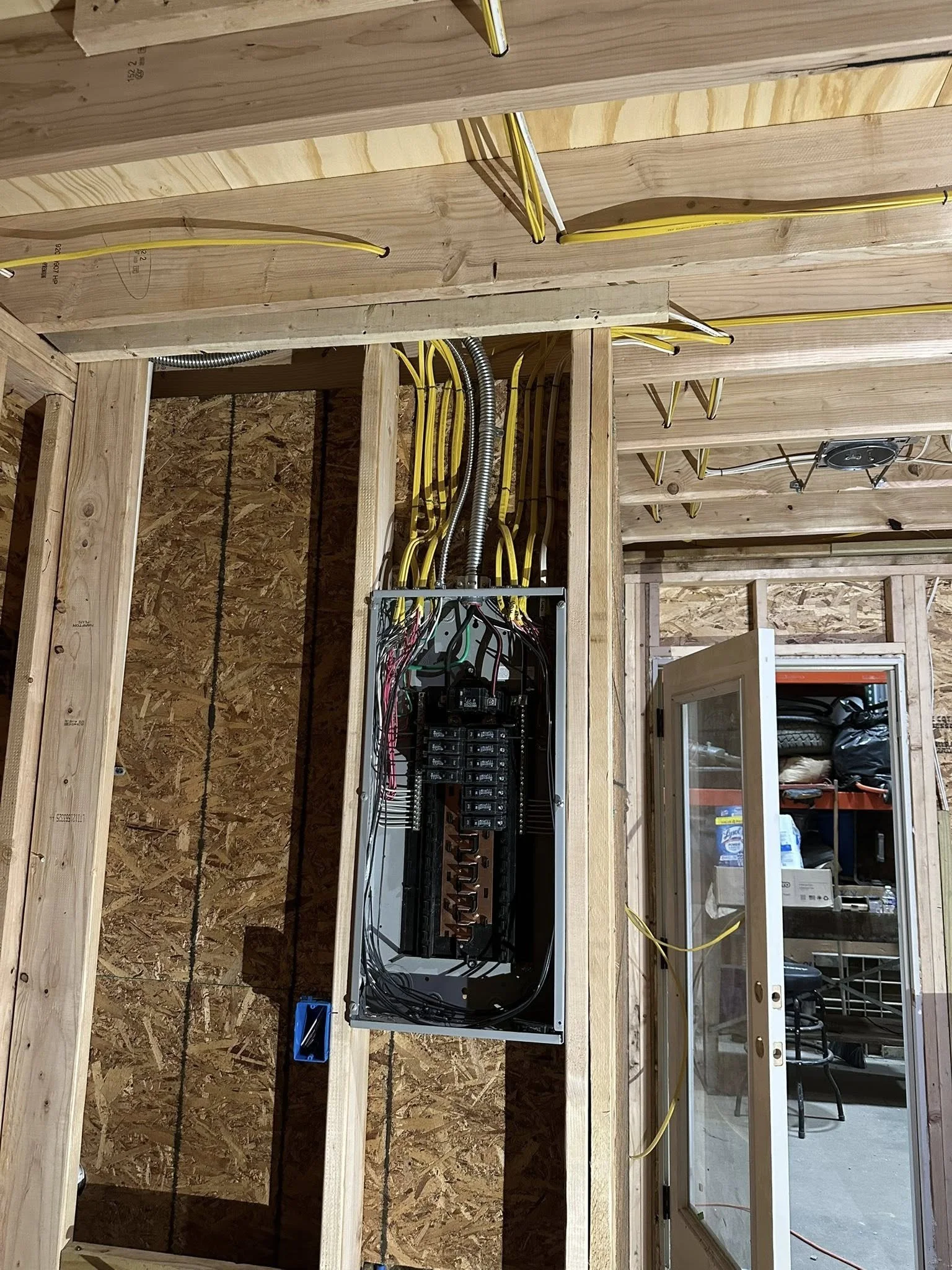 Electrical wiring inside a panel box in a construction site, with yellow wires running through a wooden framework.