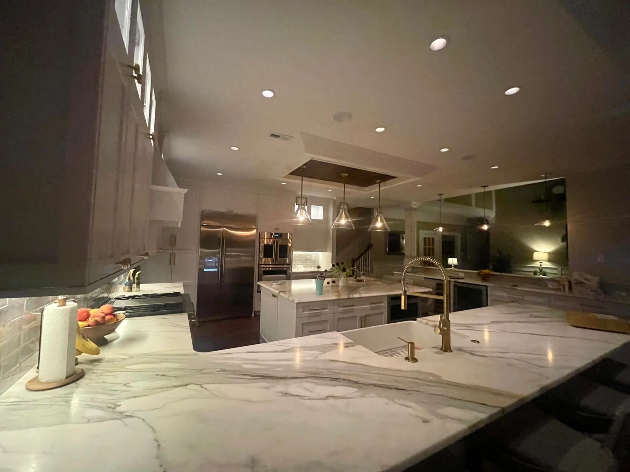 Modern kitchen with marble countertops, stainless steel appliances, pendant lighting, and a sink with a gooseneck faucet.