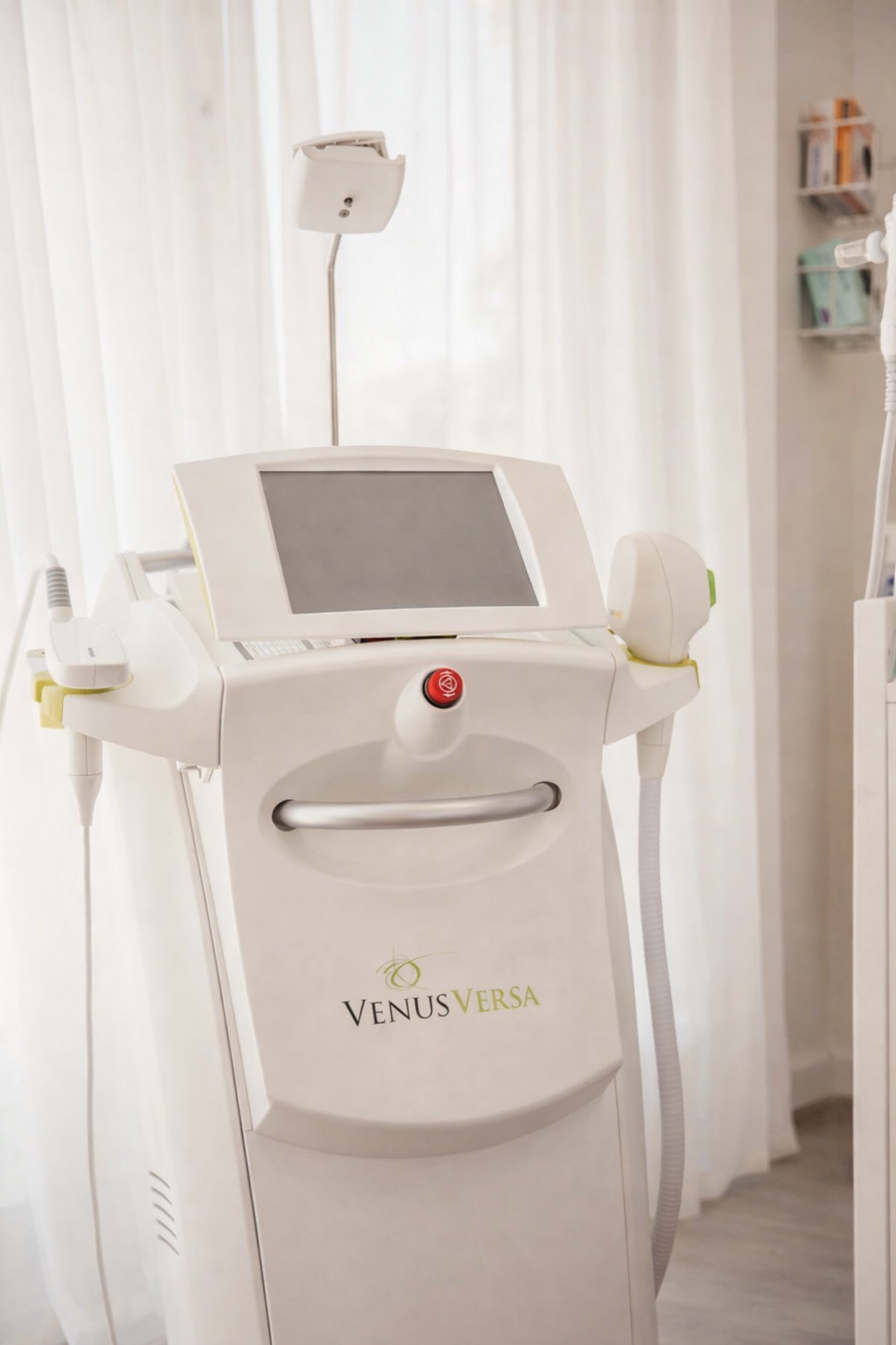 A medical device labeled Venus Versa with a touchscreen display, placed in a clinical setting with white curtains and shelves in the background.