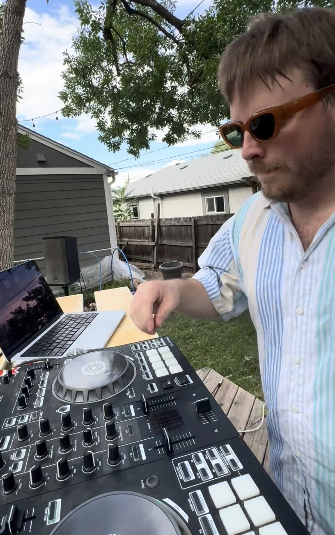 ctrlz experience, a sweaty bearded Colorado DJ and producer, performs an outdoor electronic music set surrounded by nature at a lively garden party.