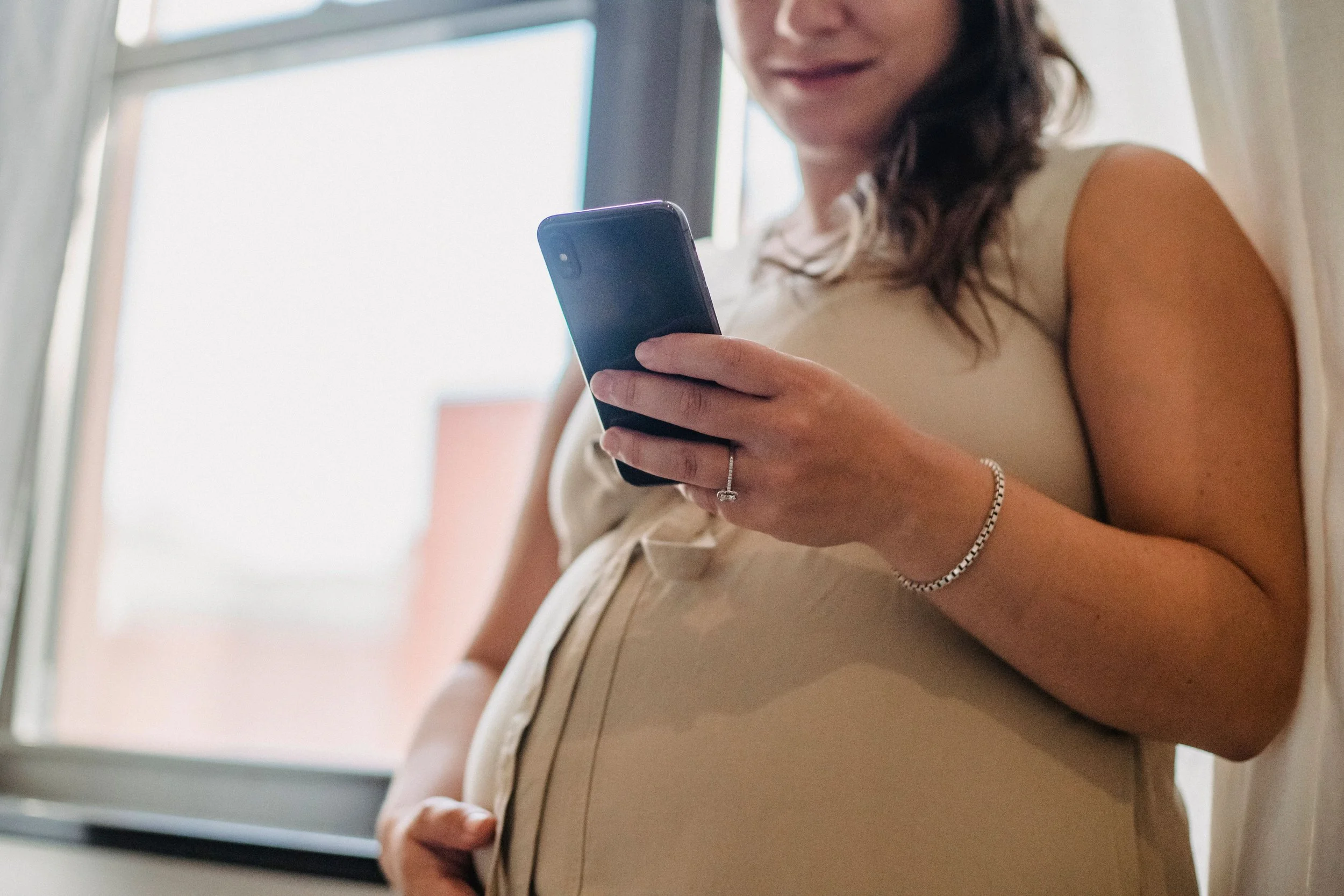 Pregnant woman looking down at phone.