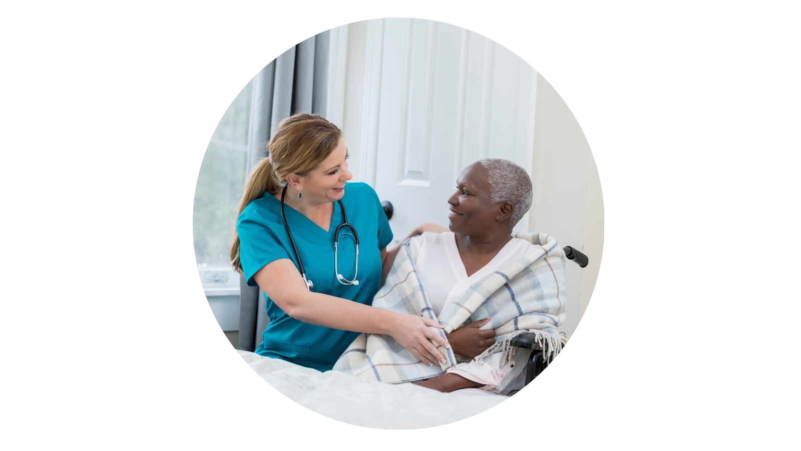 Healthcare professional smiling at patient in a hospital room.