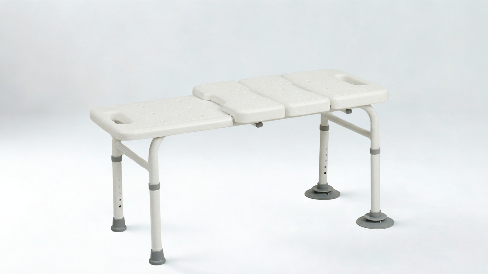 A white medical shower wheelchair with adjustable footrests and rubberized feet.