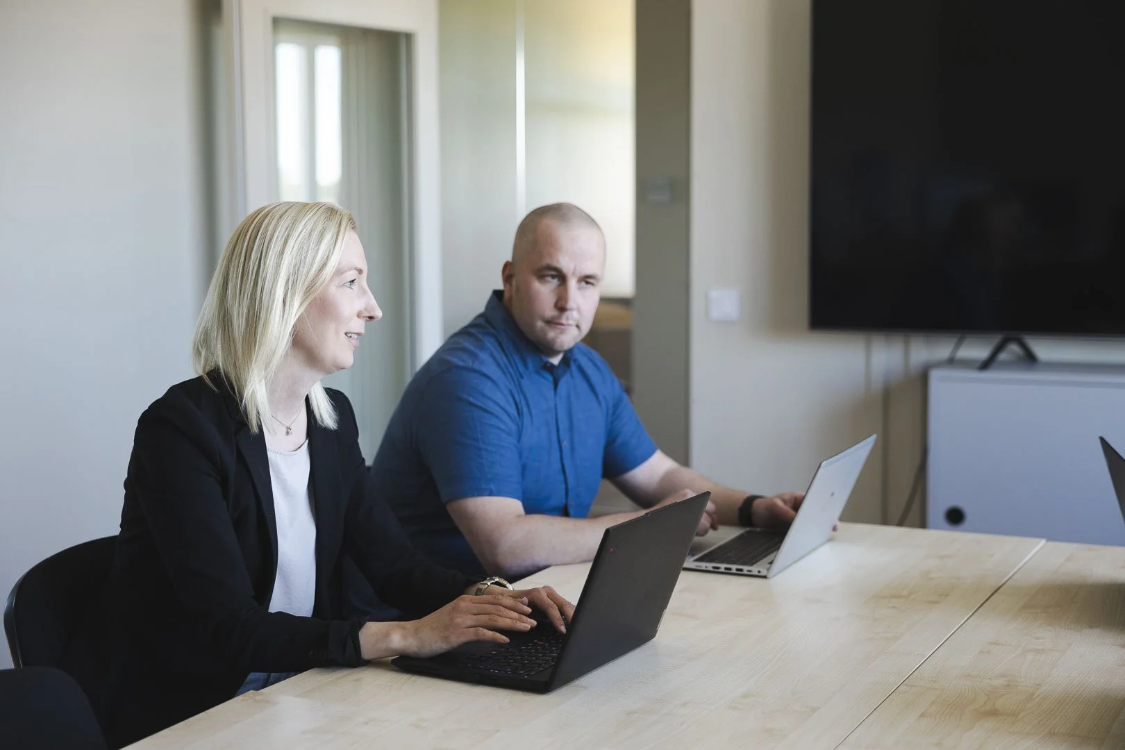Två medarbetare arbetar vid sina datorer på ÅV-Byggs kontor
