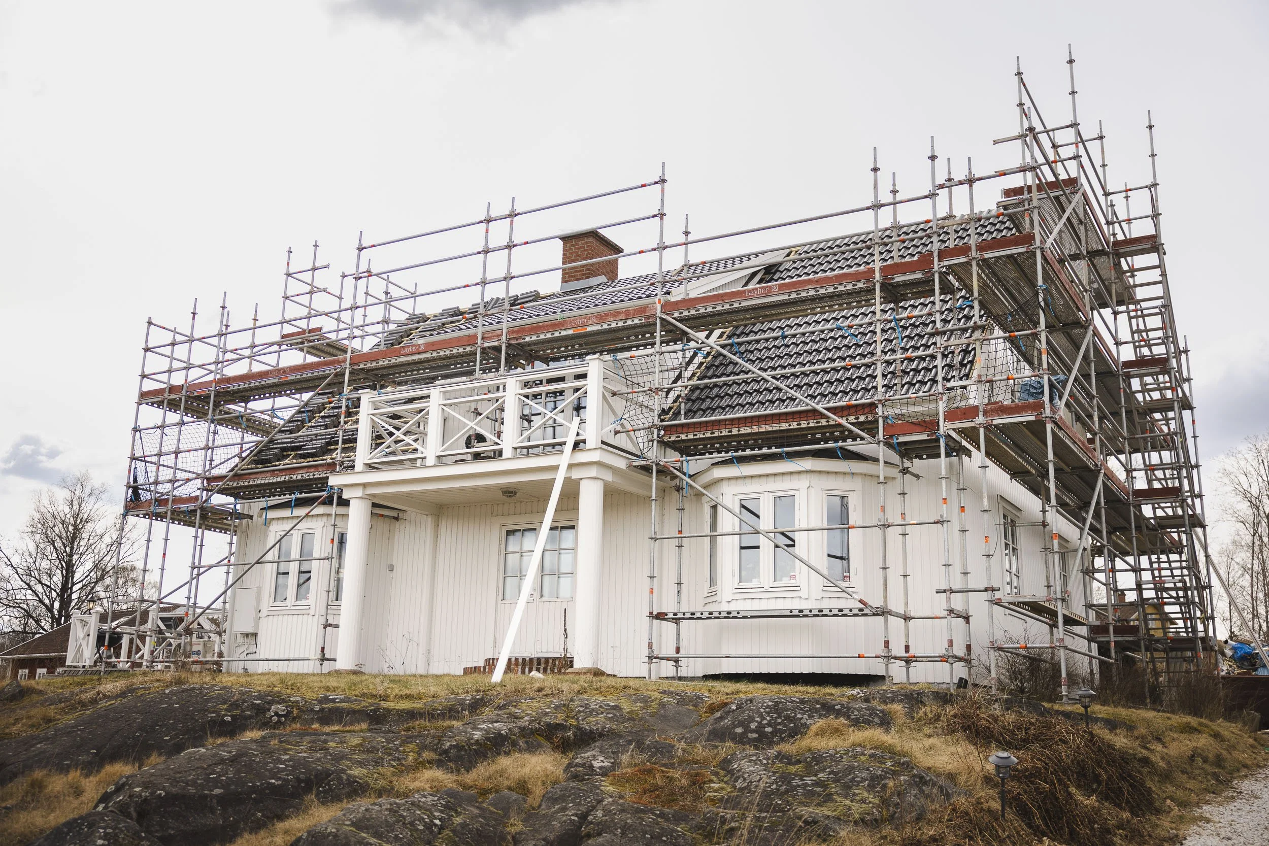 Villa med byggnadsställning runt fasaden vid takbyte