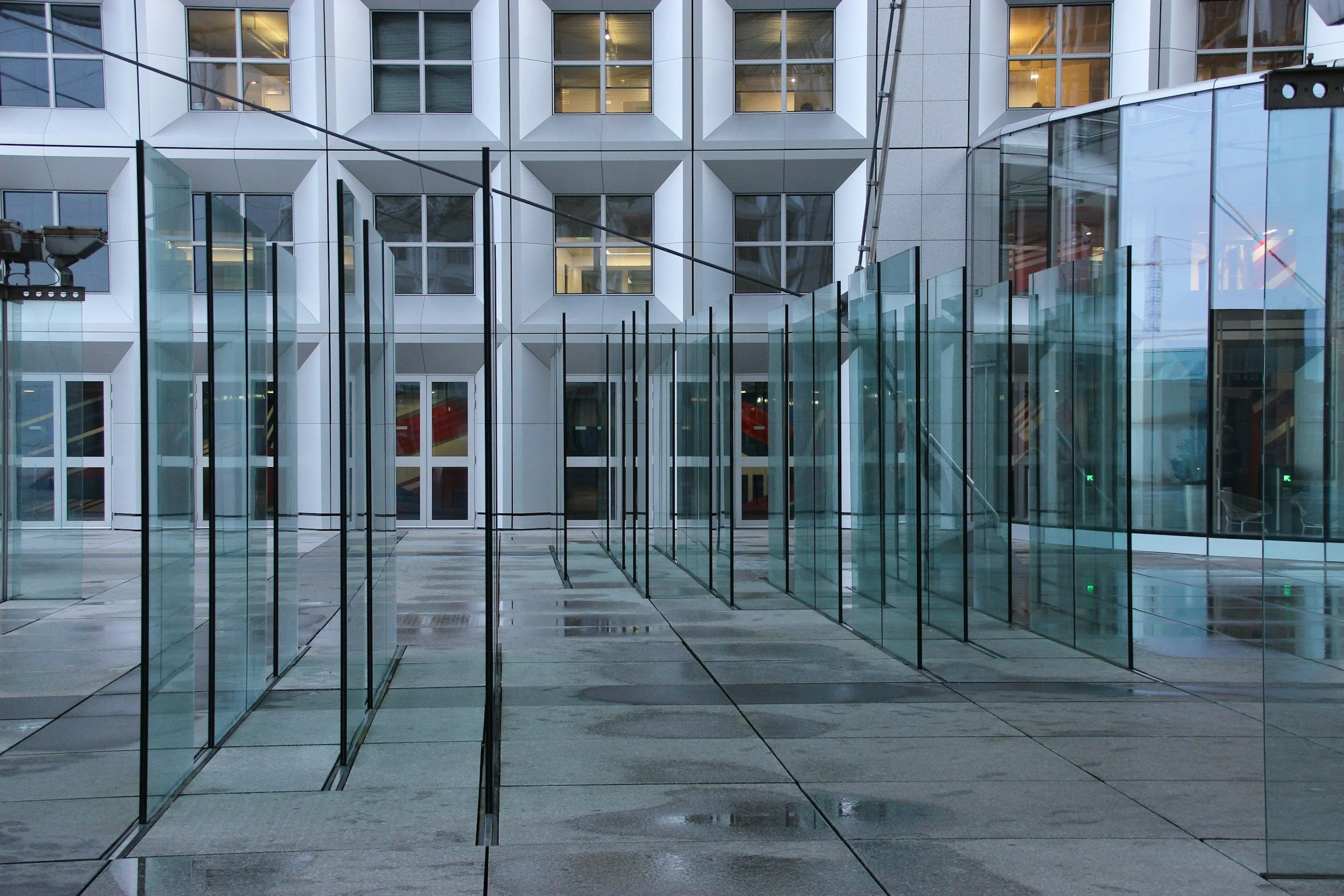 Modern building with glass windows and glass walls, reflecting the surroundings and leading inside.