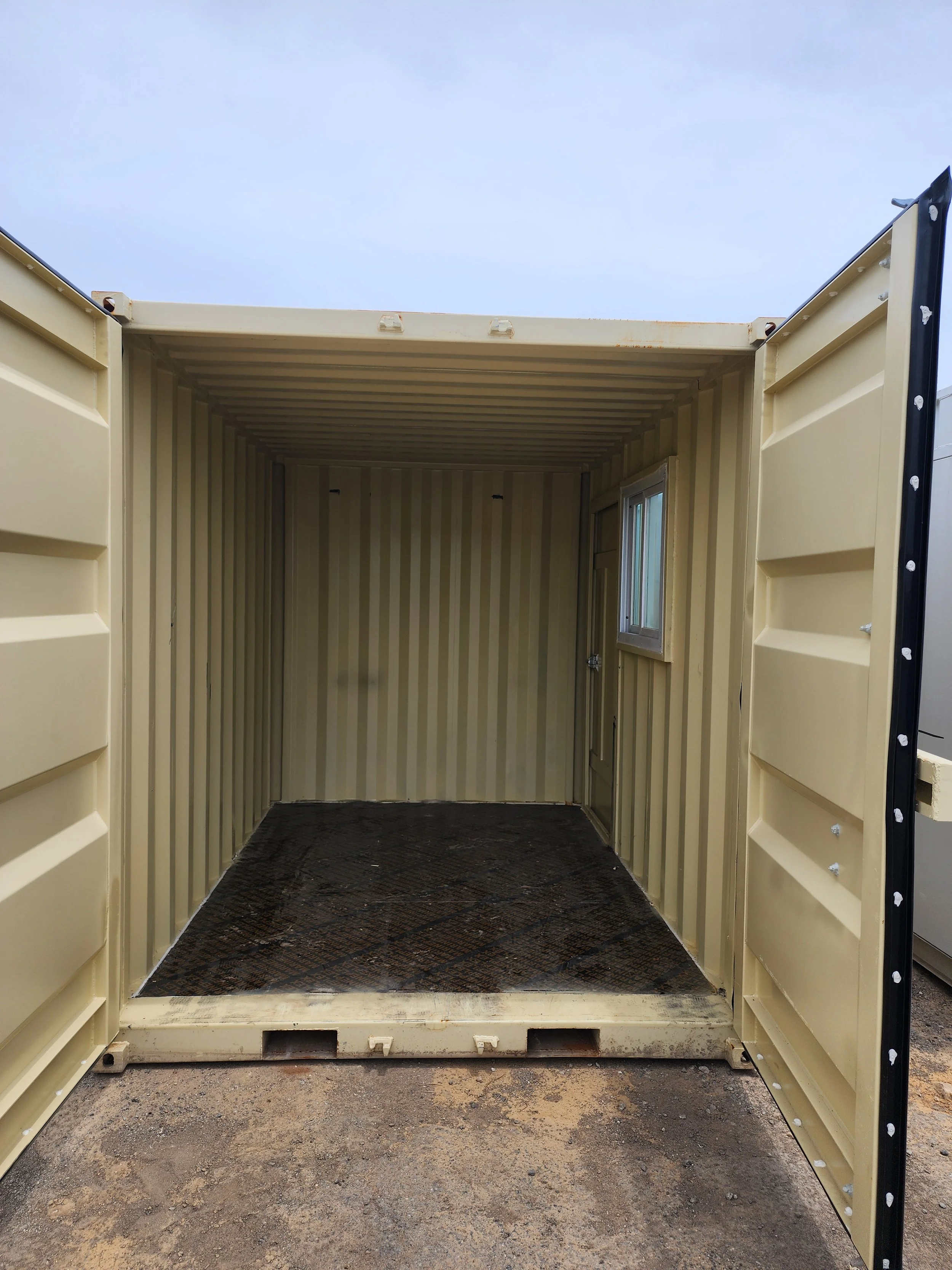 Empty beige shipping container with open doors, ribbed metal interior, carpeted floor, and side window