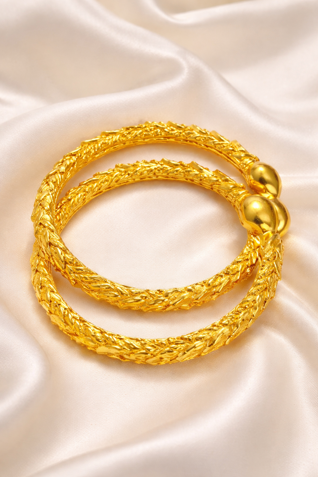 Elegant gold bangles on silk fabric.png