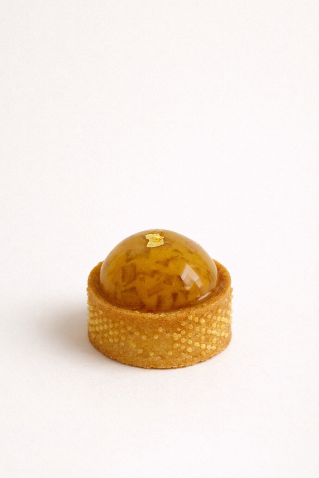 Close-up of an elegant caramelised apple tart petit four with a jewel-like amber glaze. High tea dessert catering Double Bay.