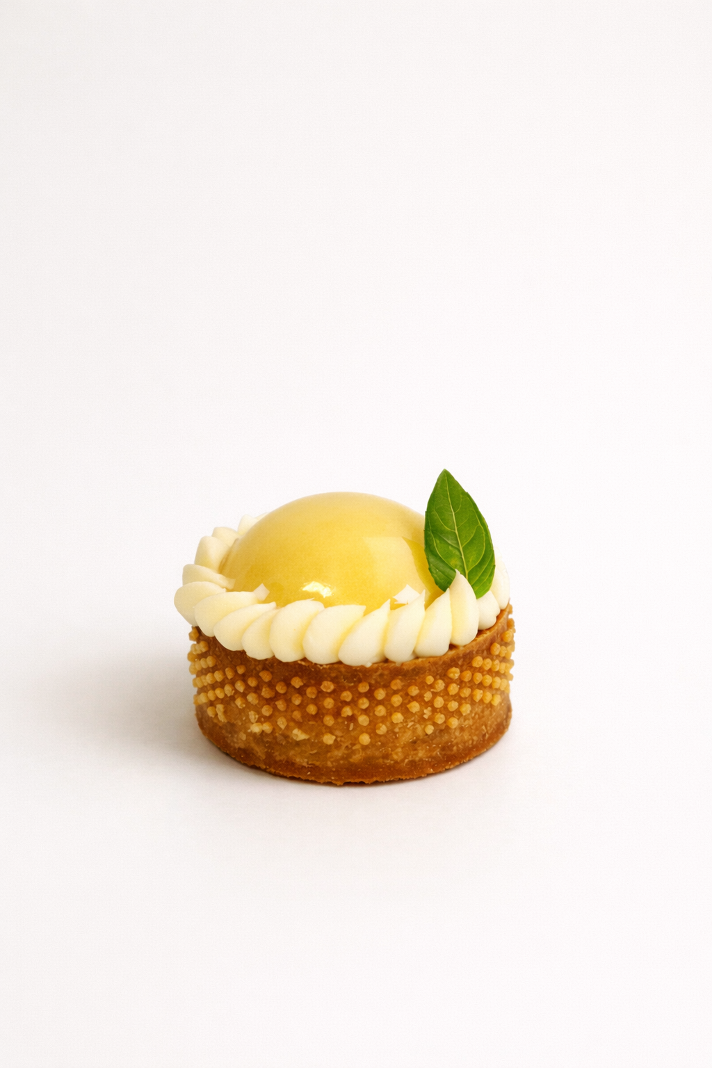 Close-up of a premium lemon basil tart petit four with glossy glaze and fresh basil leaf. Luxury dessert delivery in Sydney.