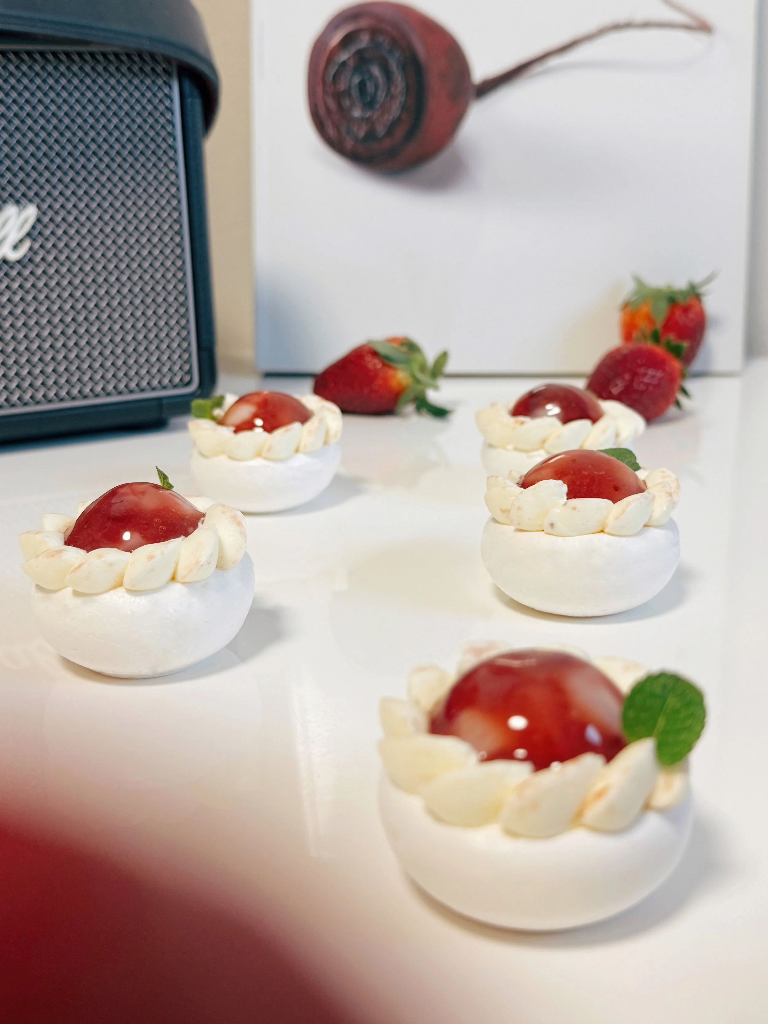 Several strawberry lychee pavlovas styled with fresh fruit. Elegant gluten free petit fours for bridal shower dessert catering Sydney.