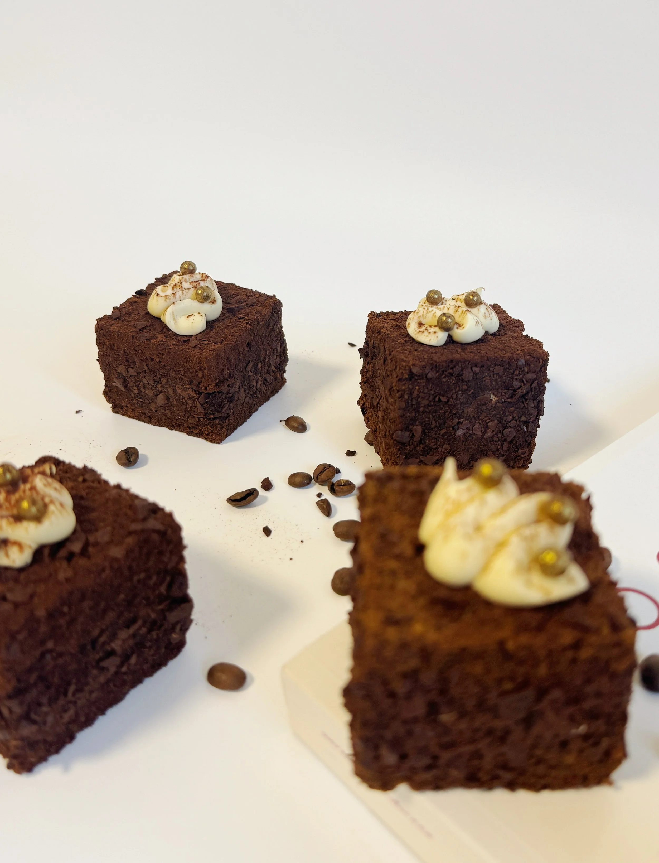 A beautiful spread of tiramisu cubes styled with freshly roasted coffee beans. Handcrafted mini desserts for dinner parties Sydney.