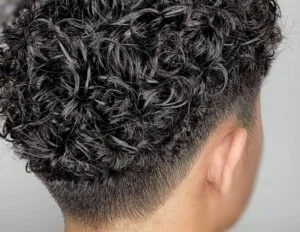 Back view of a person's head with short, curly permed hair