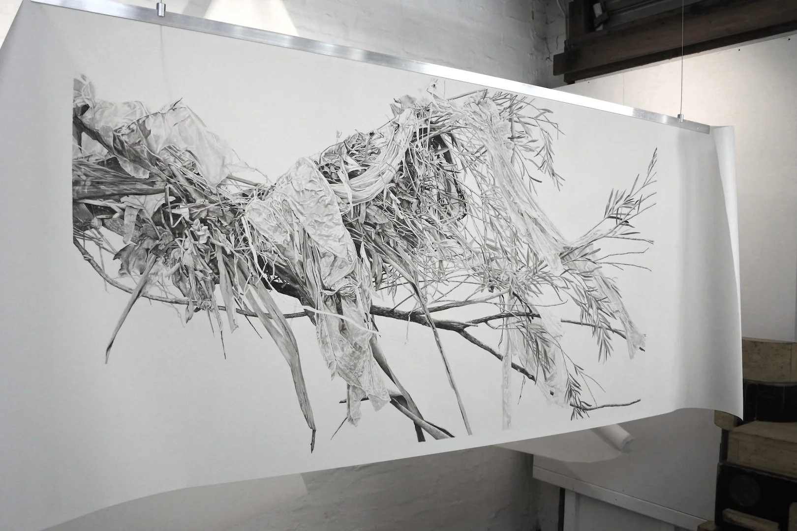 A black and white sketch of a tangled pile of leaves, twigs, fabric and foliage.