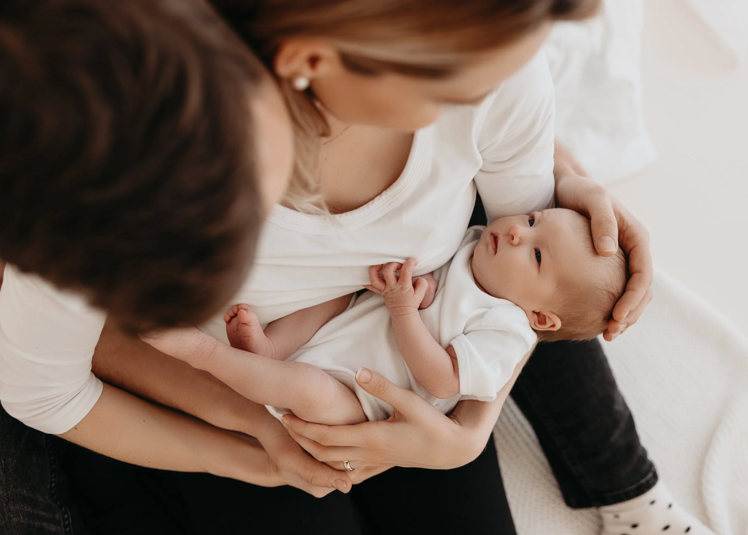 Eine Frau hält ein Baby auf ihrem Schoß, beide schauen sich liebevoll an.