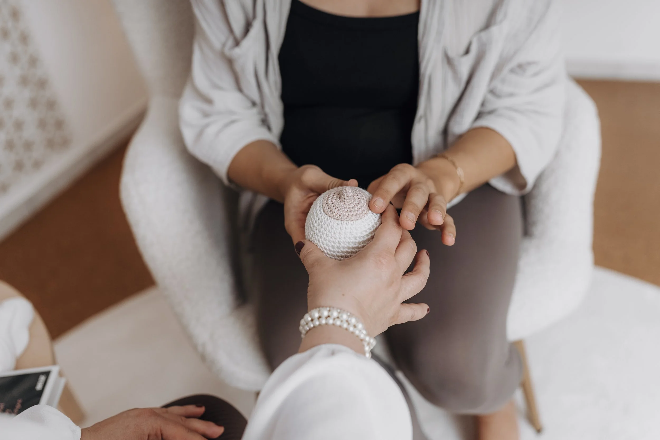 Doula zeigt schwangerer Frau zur Geburtsvorbereitung ein Brustmodell