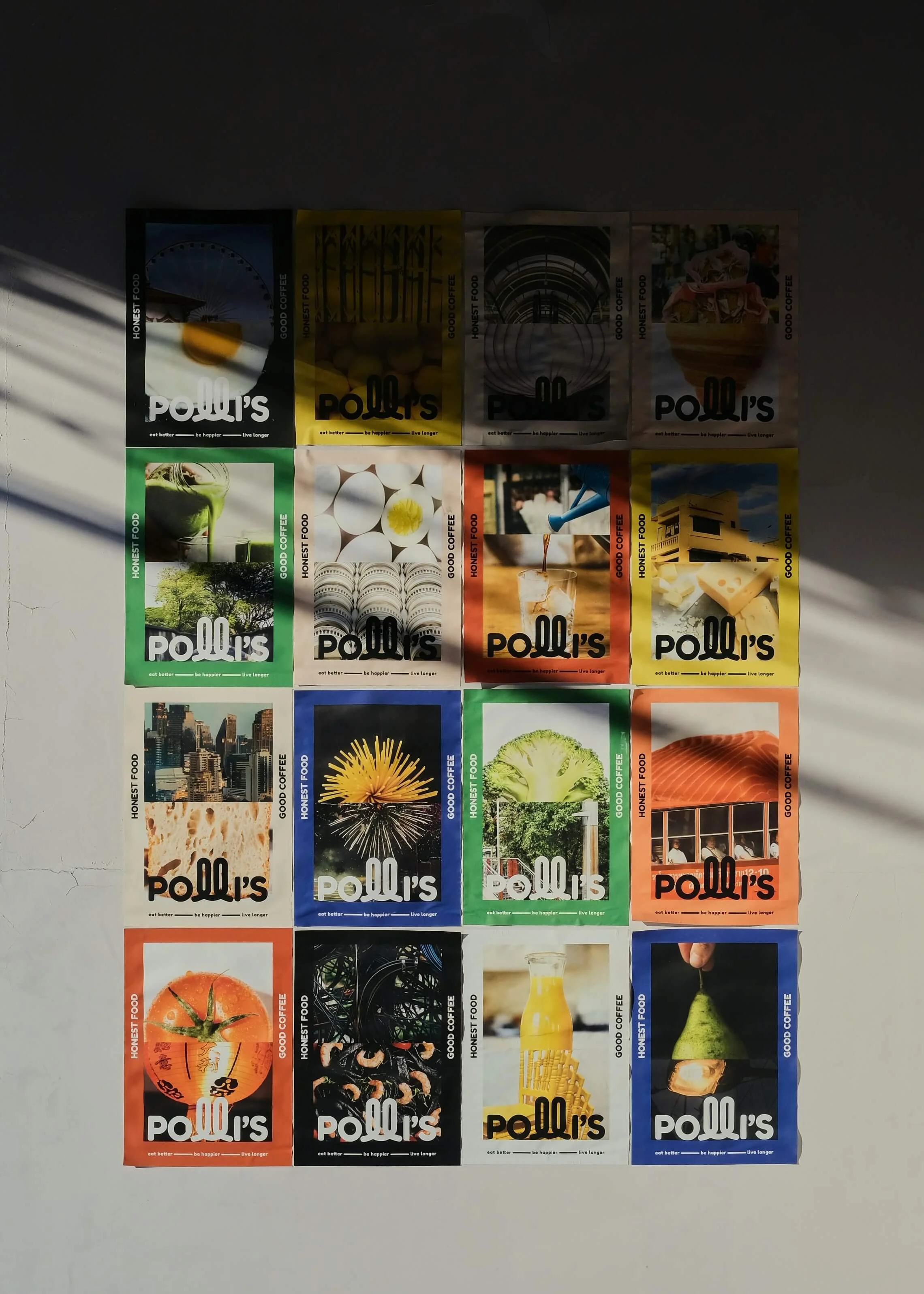 Colorful posters on a wall featuring various images, including a ferris wheel, eggs, a drink, city skyline, flower, broccoli, salmon, tomato, bicycle wheels, and a pear.