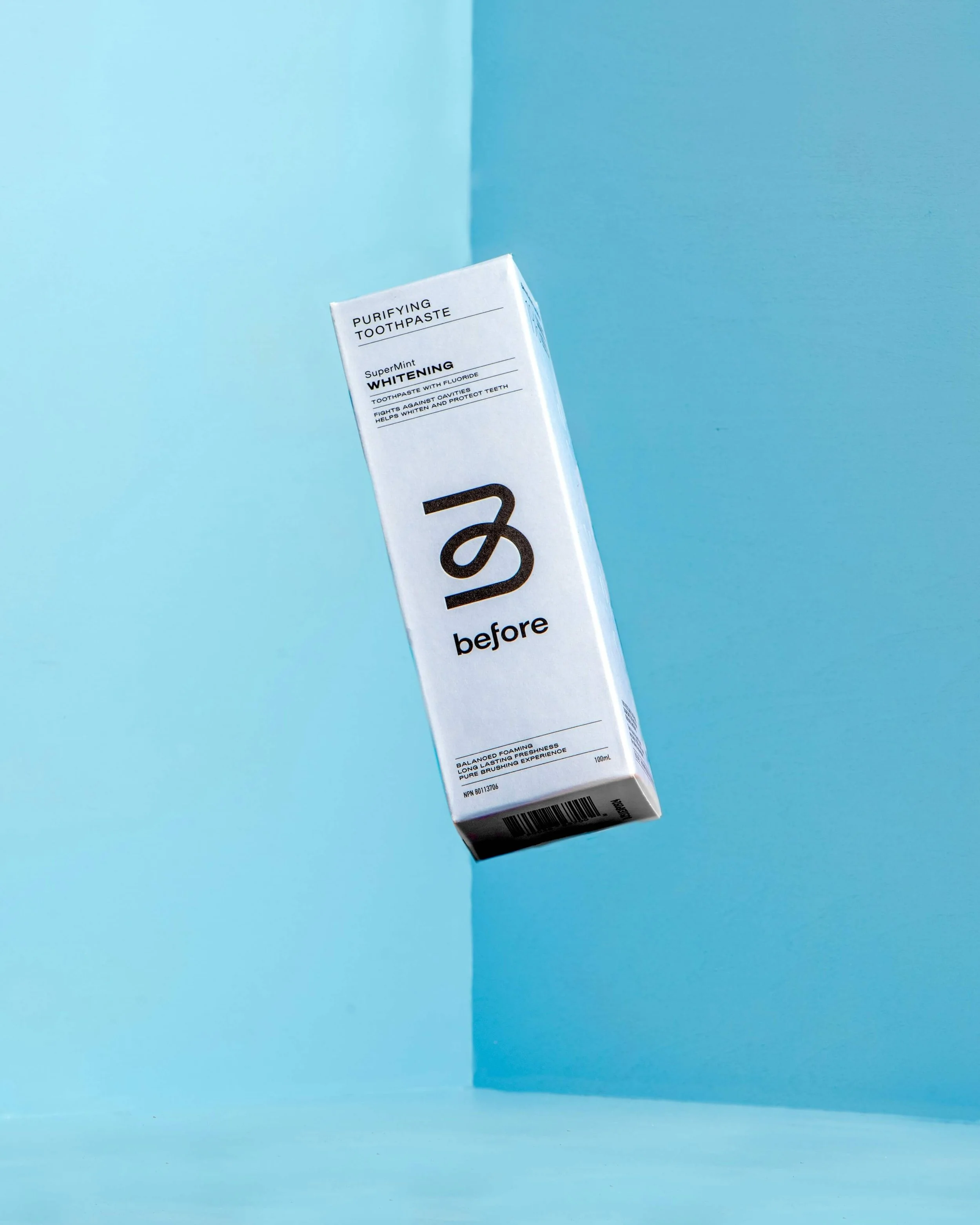 A white box of toothpaste labeled 'before' with a black logo, set against a blue background.