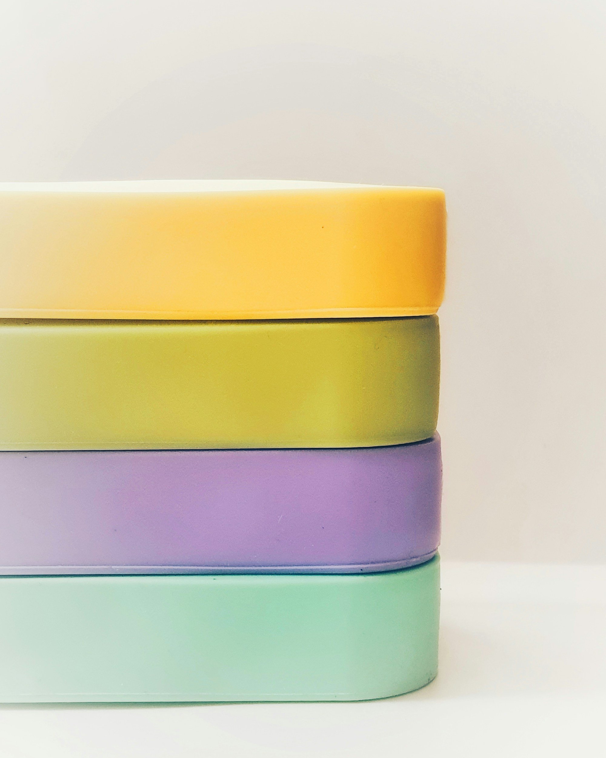 Stacked pastel-colored rectangular boxes in yellow, green, purple, and mint green on a white background.