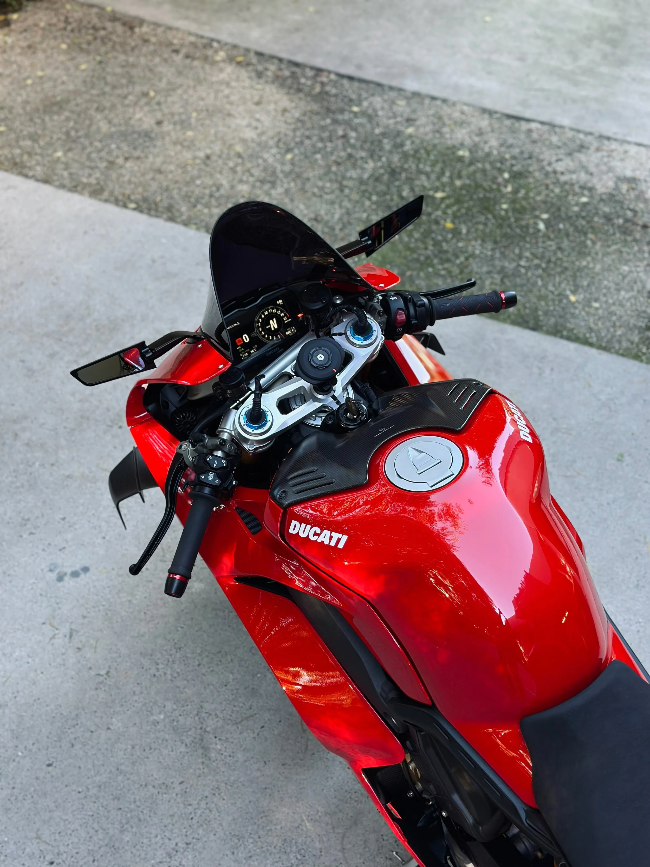 Red Ducati motorcycle parked on concrete pavement, viewed from above.