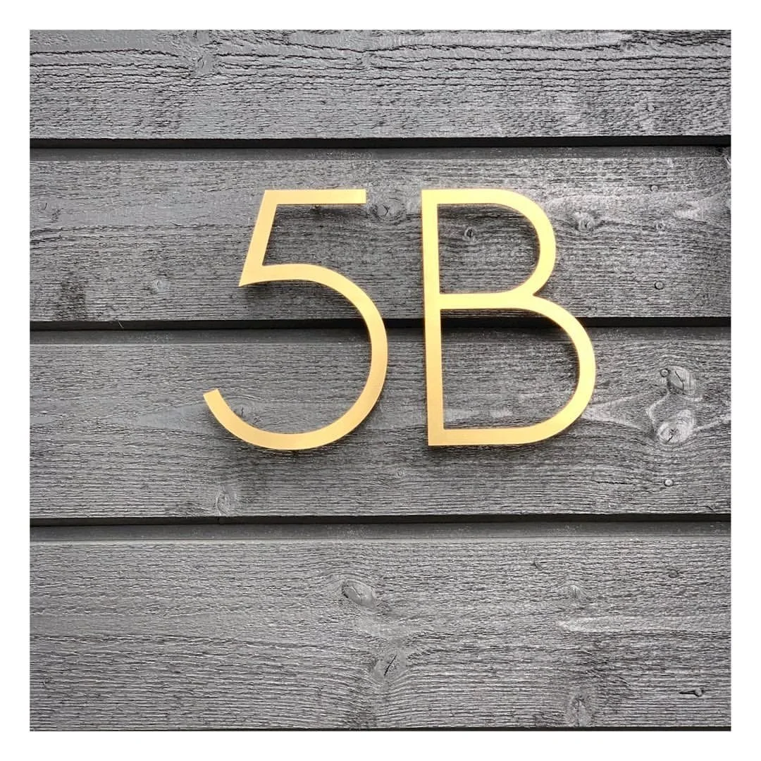 Guldnamn på en trävägg som visar '5B'.