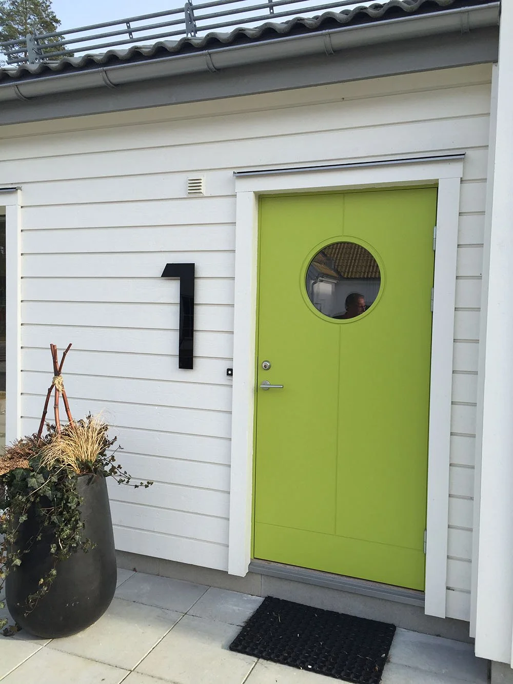 Husnummer 1 i pulverlackerat matte svart rostfritt stål på vit träfasad