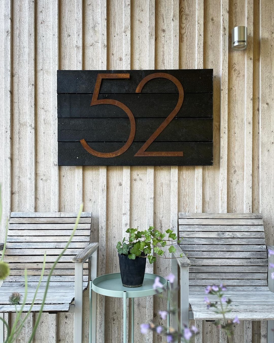 Husnummer 52 i rostig cortenstål på beige husvägg