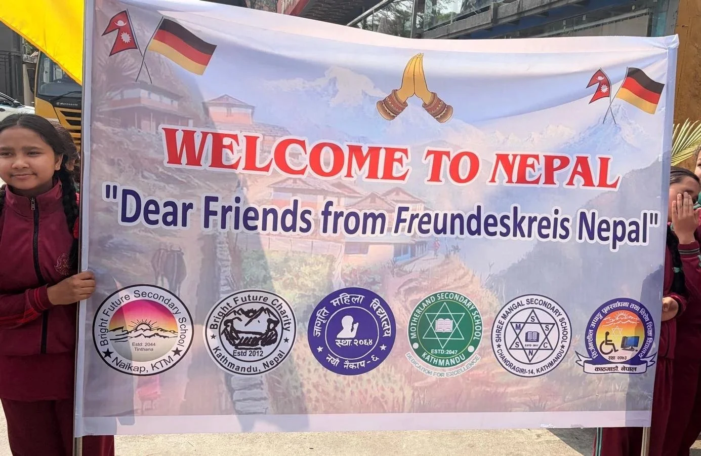Kinder halten Willkommens-Plakat für den Freundeskreis Nepal