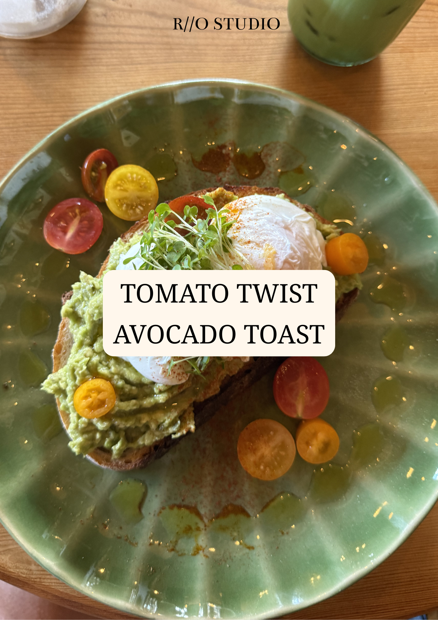 A plate of avocado toast topped with an egg and microgreens, garnished with cherry tomatoes and drizzled with oil, on a green ceramic plate.