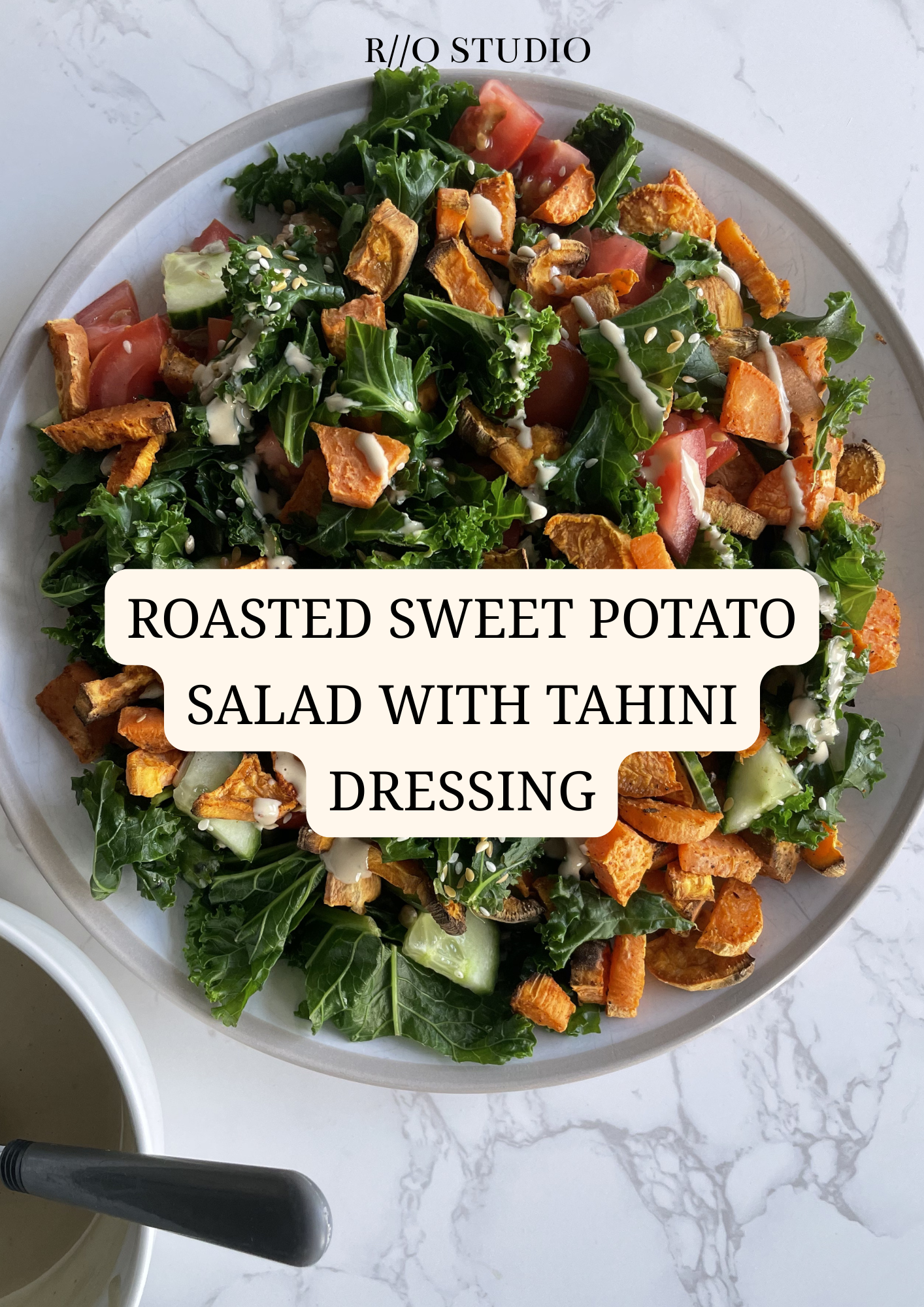 Roasted sweet potato salad with a tahini dressing made with honey and olive oil, sprinkled with sesame seeds with tomatoes and cucumber and spinach