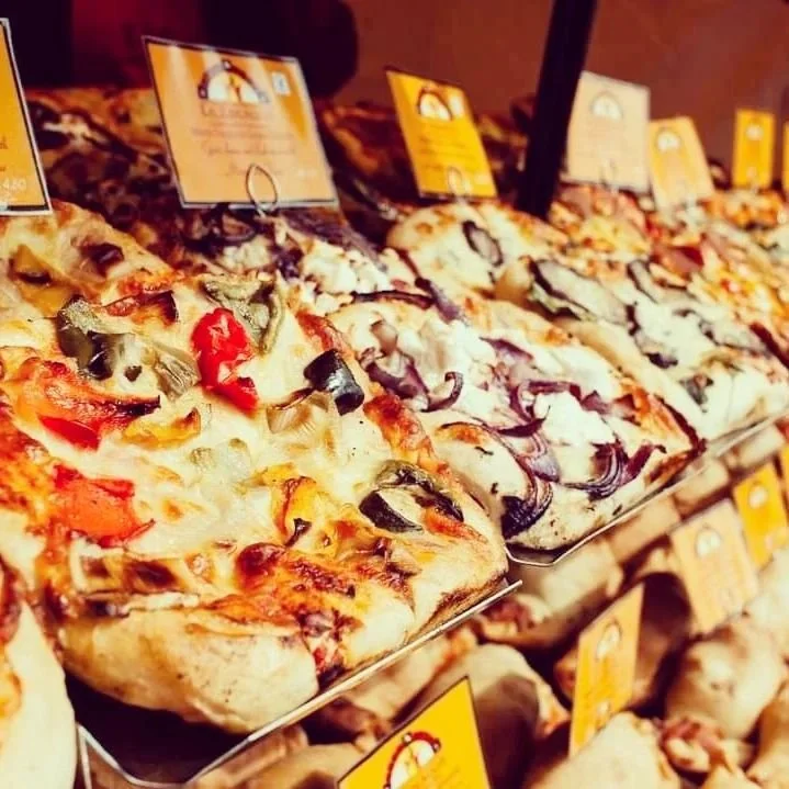 Various types of artisan focaccia displayed on a market stall with price tags.