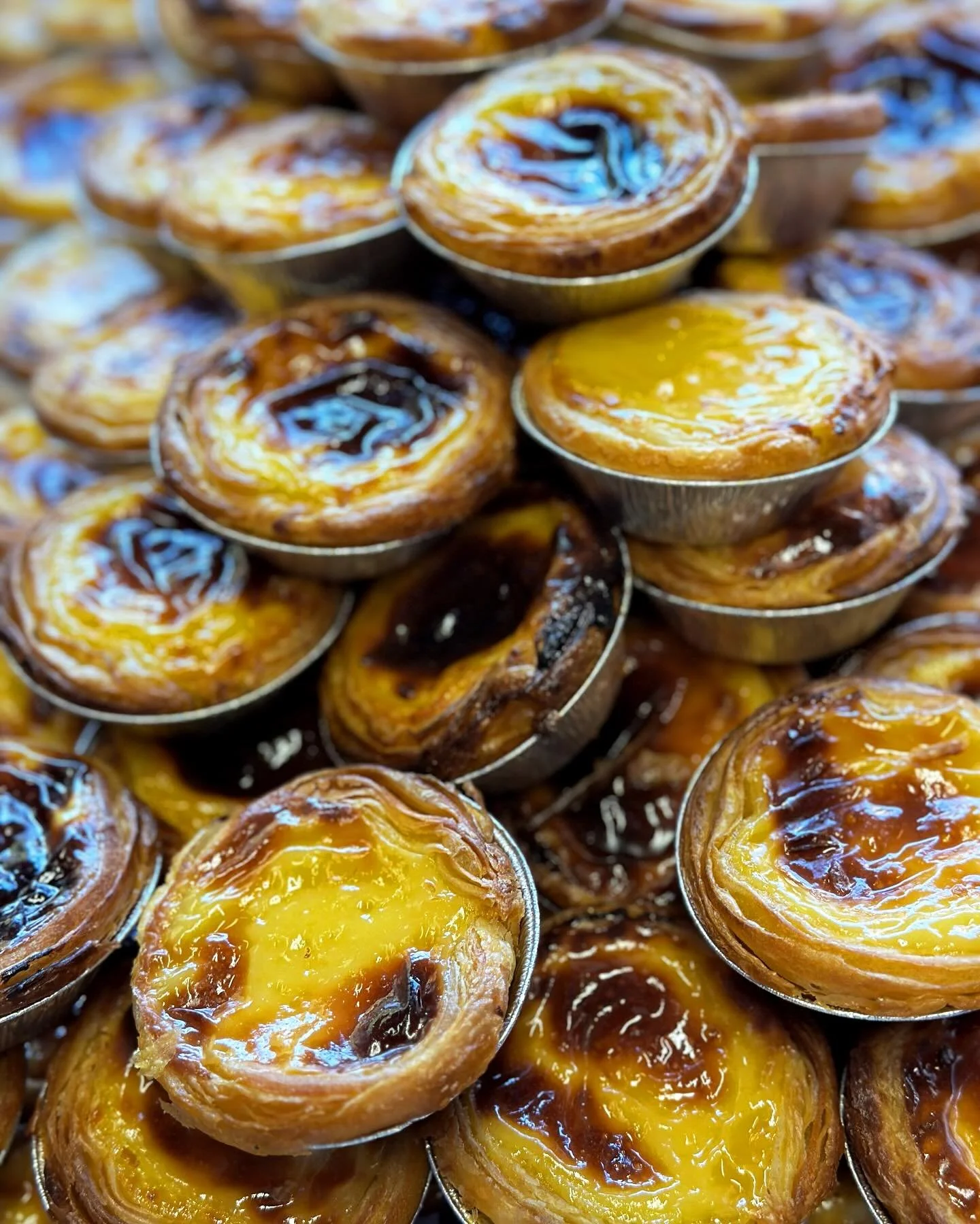 Close-up of multiple Portuguese egg tarts with caramelized tops.
