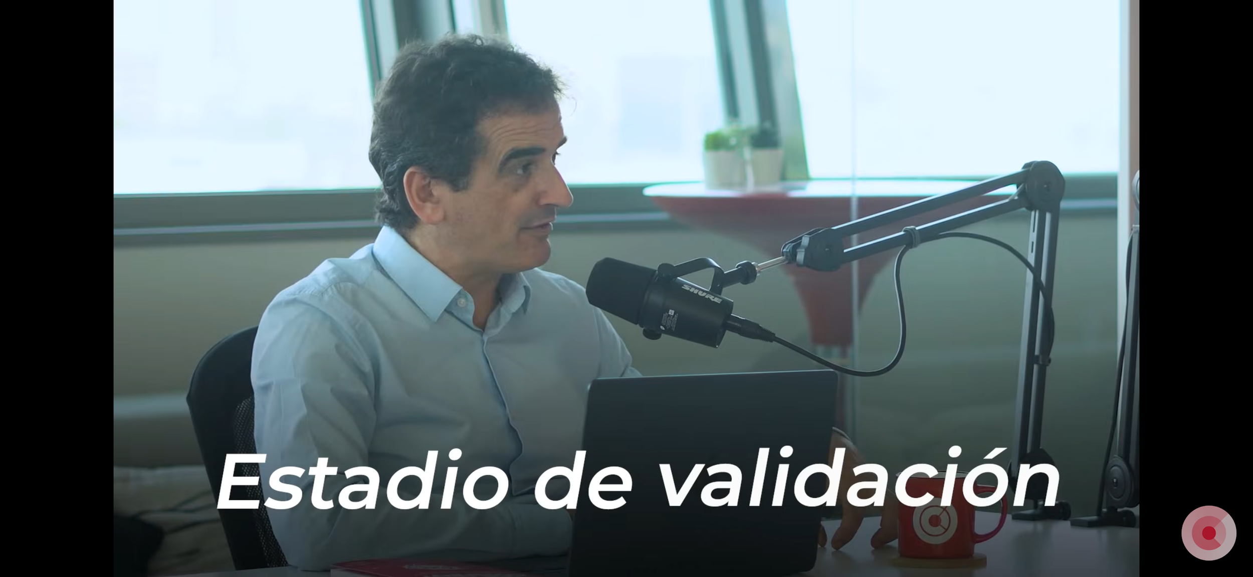 David Tomás CEO Cyberclick sentado en oficina, usando micrófono para grabar o transmitir, con la leyenda 'Estado de validación'