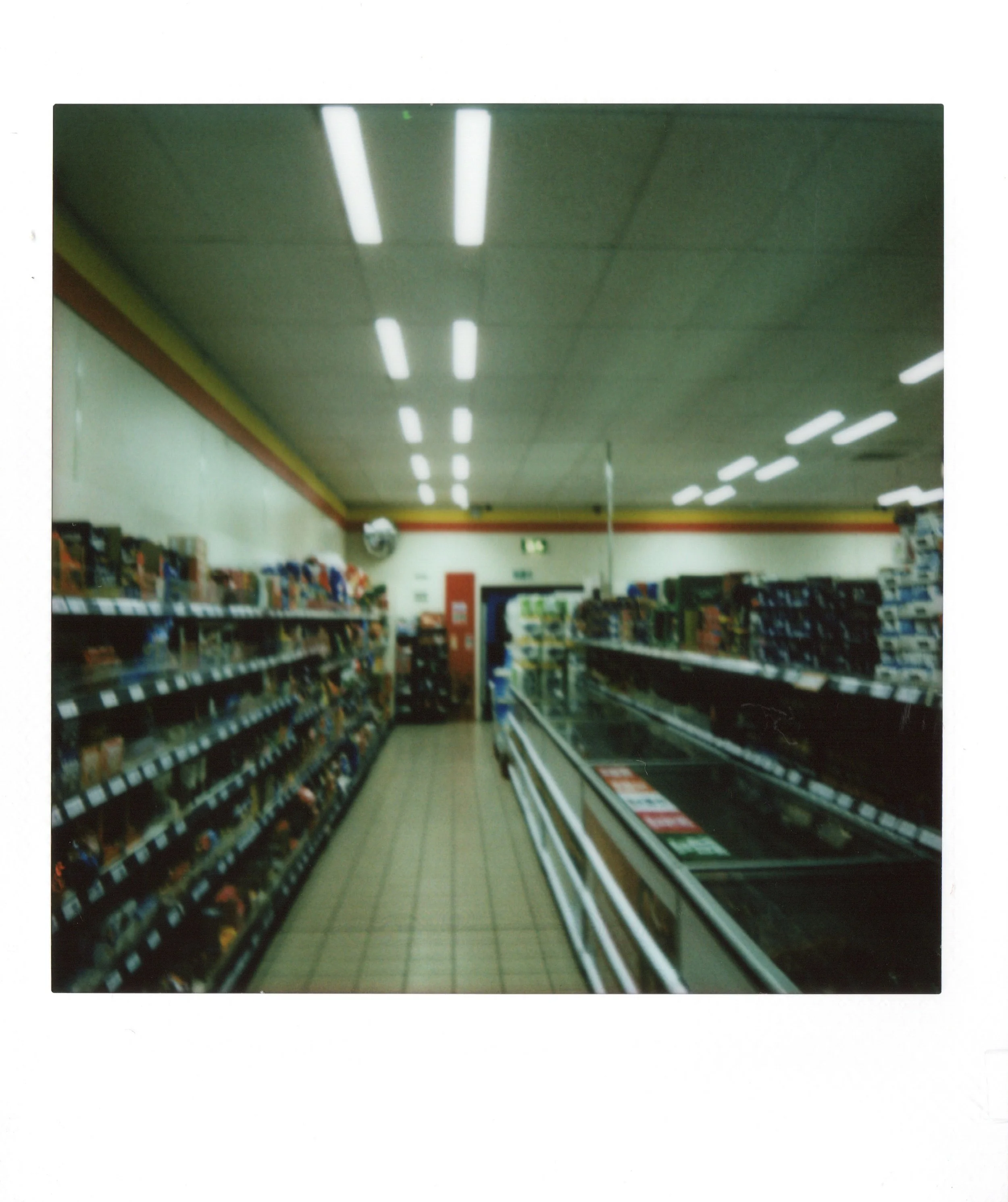 Empty supermarket aisle with shelves on both sides and fluorescent lighting