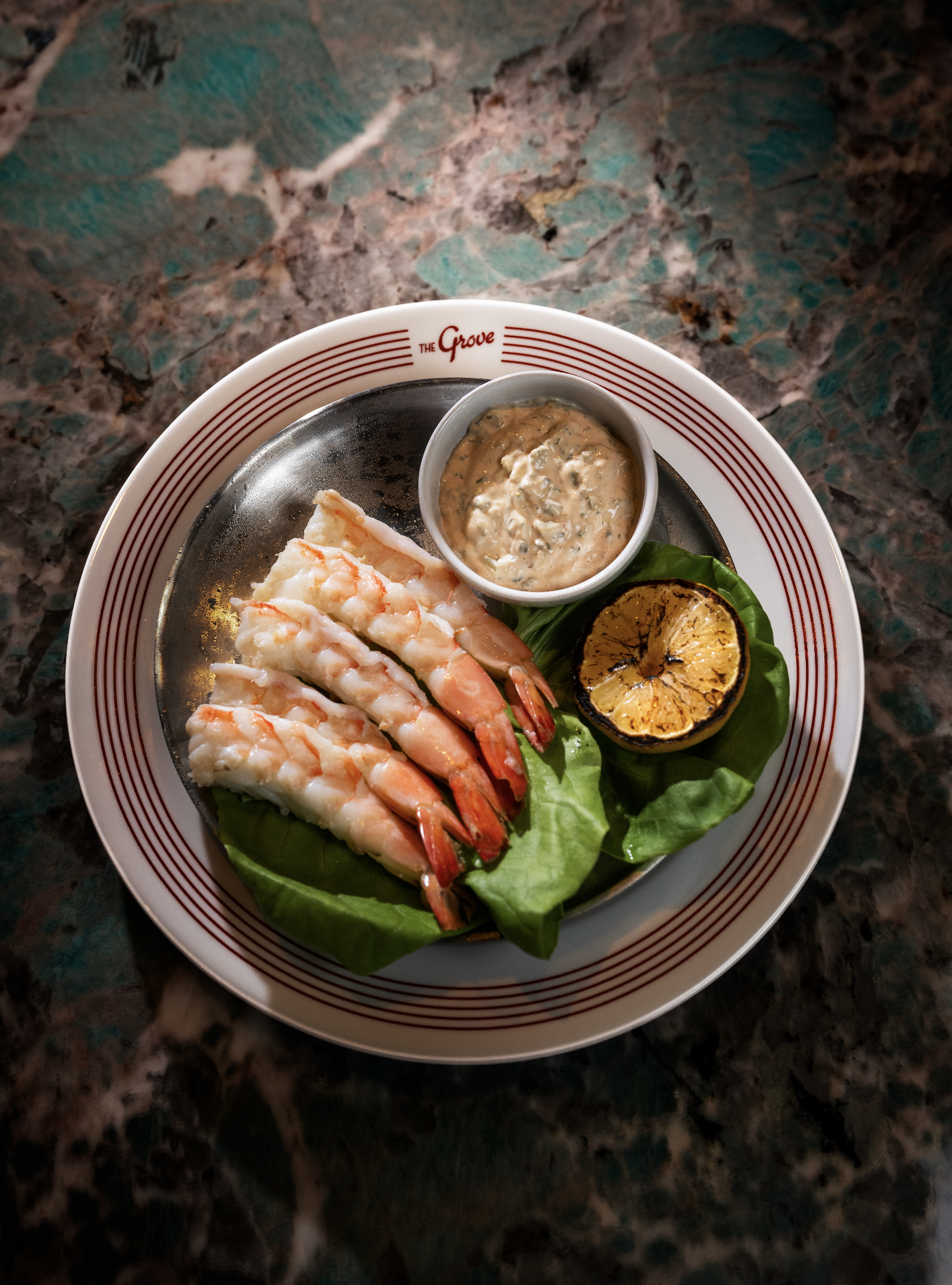 Cocktail Shrimp with lemon, garnished with greens and accompanied by a dipping sauce