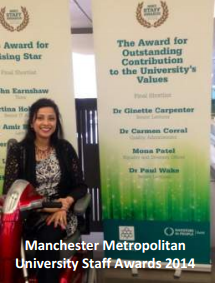 NADSN | National Association of Disabled Staff Networks | Mona Patel Smiling While Seated in a Mobility Scooter in Front of Award Banners at the 2014 Manchester Metropolitan University Staff Awards
