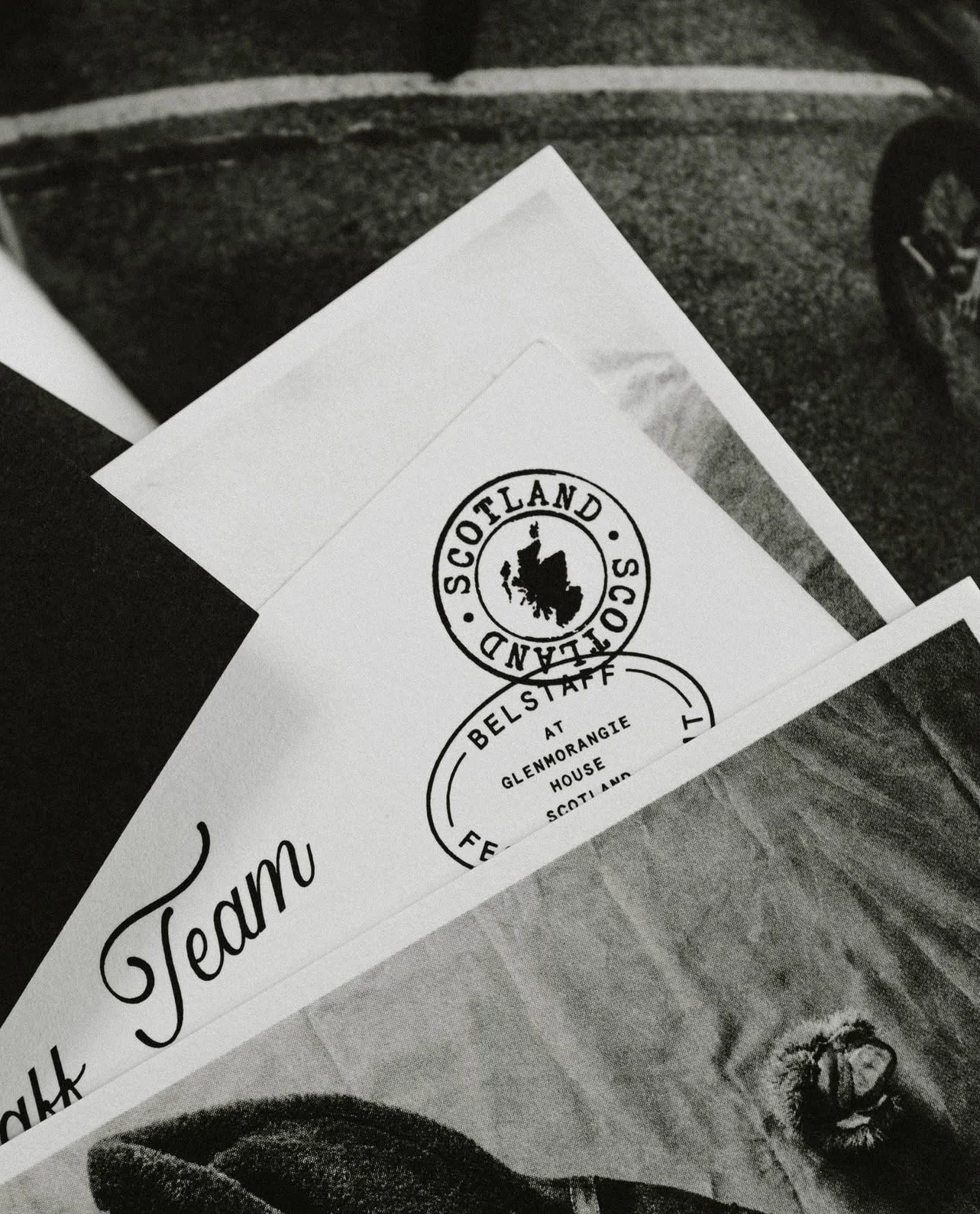 Close-up of printed papers with logos, including one with a badge for Scotland Second at Glenmorangie House, and an illustration of a man wearing glasses.