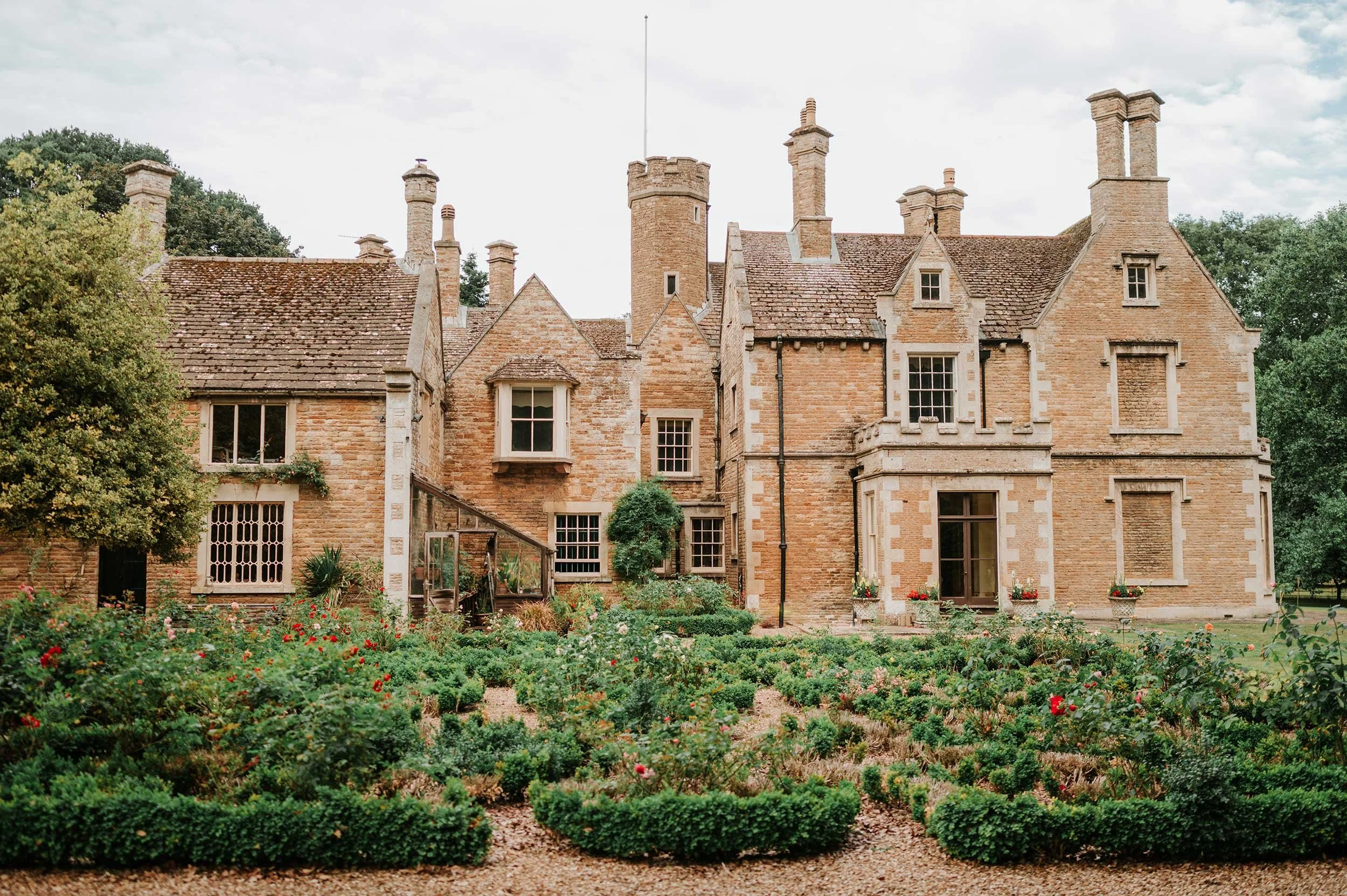 Bisbrooke Hall, surrounded by a well-maintained garden with bushes and flowers.
