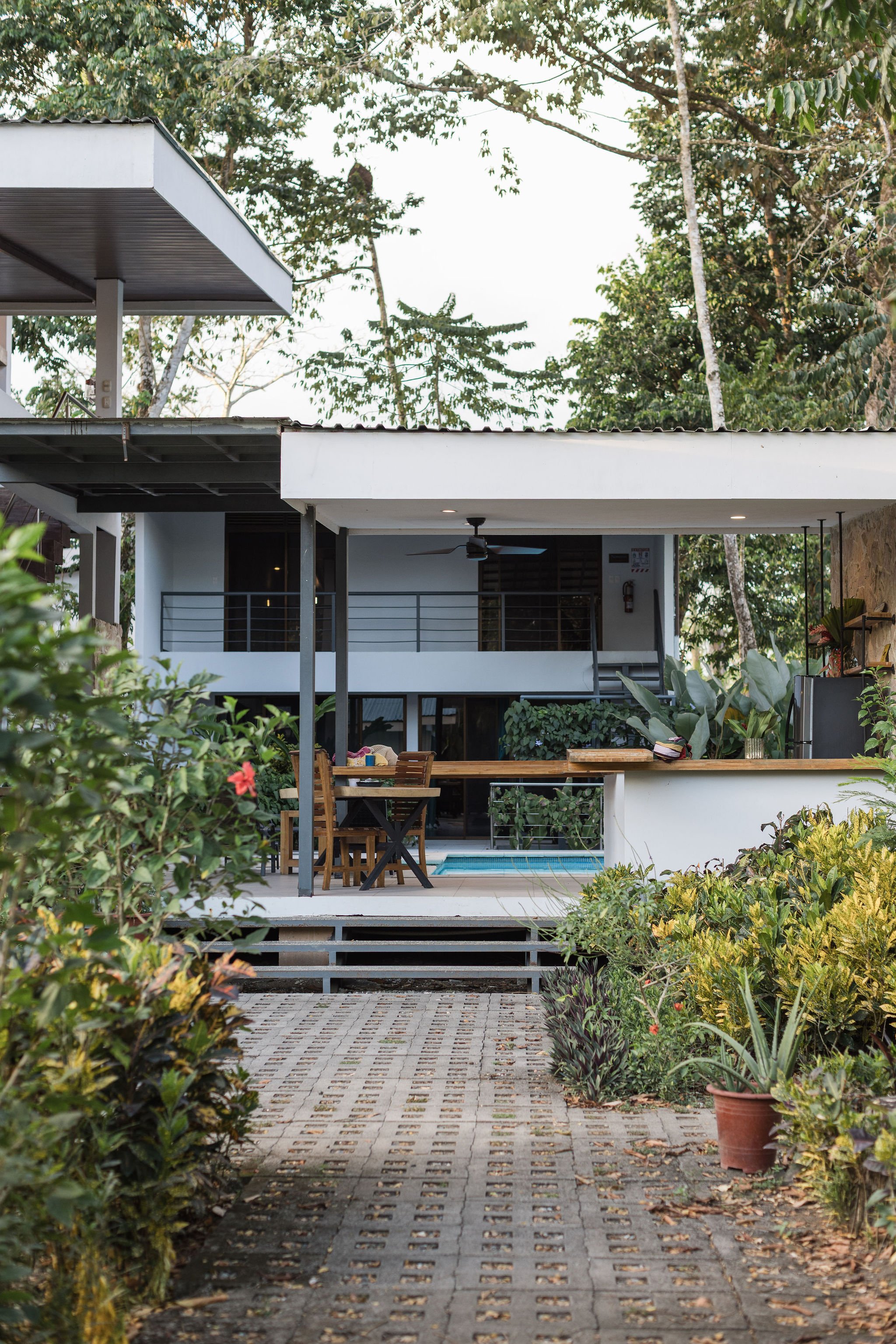 A modern house with a balcony and outdoor seating area, surrounded by lush greenery and trees, in Costa Rica.