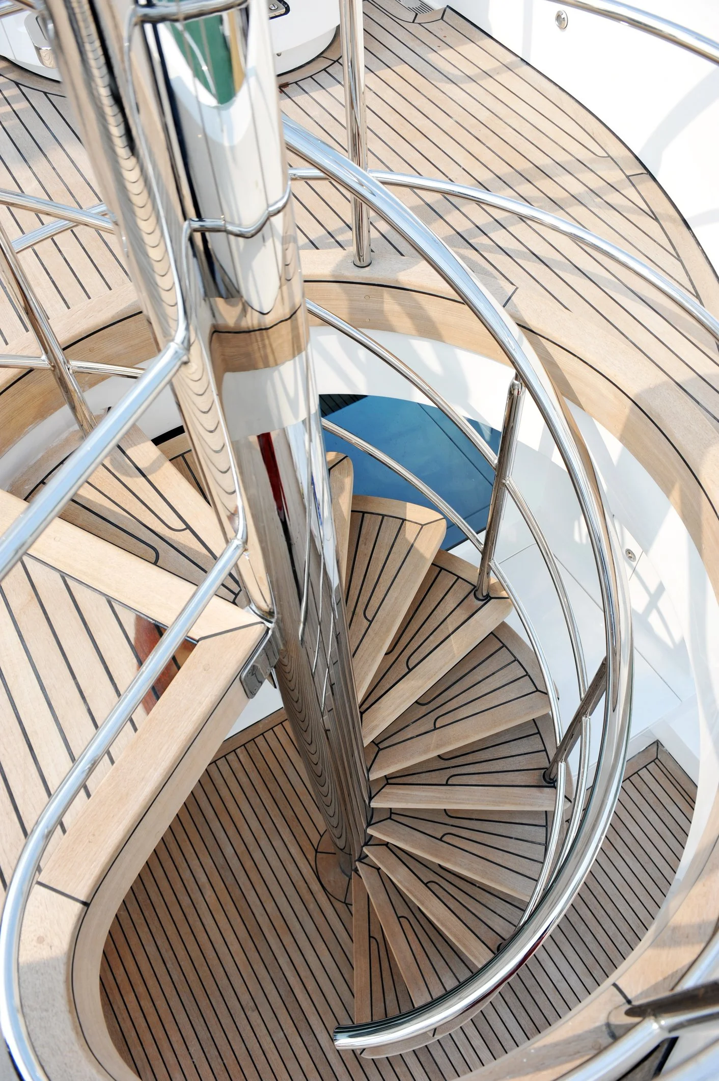 Luxury spiral staircase with wooden steps and metal railings on a boat deck, showcasing Over Oceans Yacht Interiors Projects & Management.