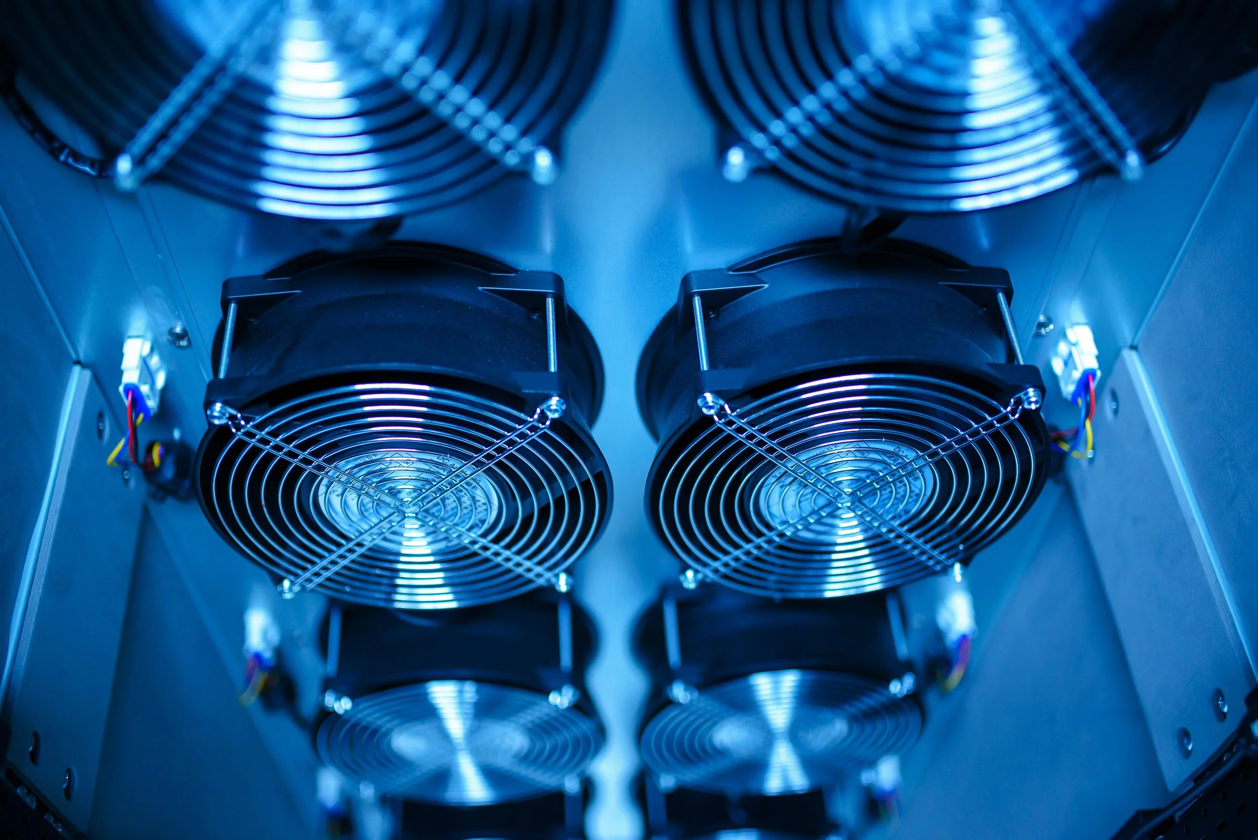 Multiple cooling fans mounted inside a computer or server case, illuminated with blue lighting.