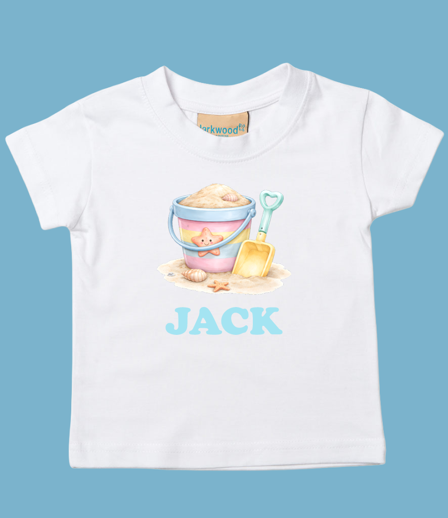 White children's t-shirt with a graphic of a beach bucket, a small shovel, seashells, and starfish, and the name 'JACK' in blue lettering.