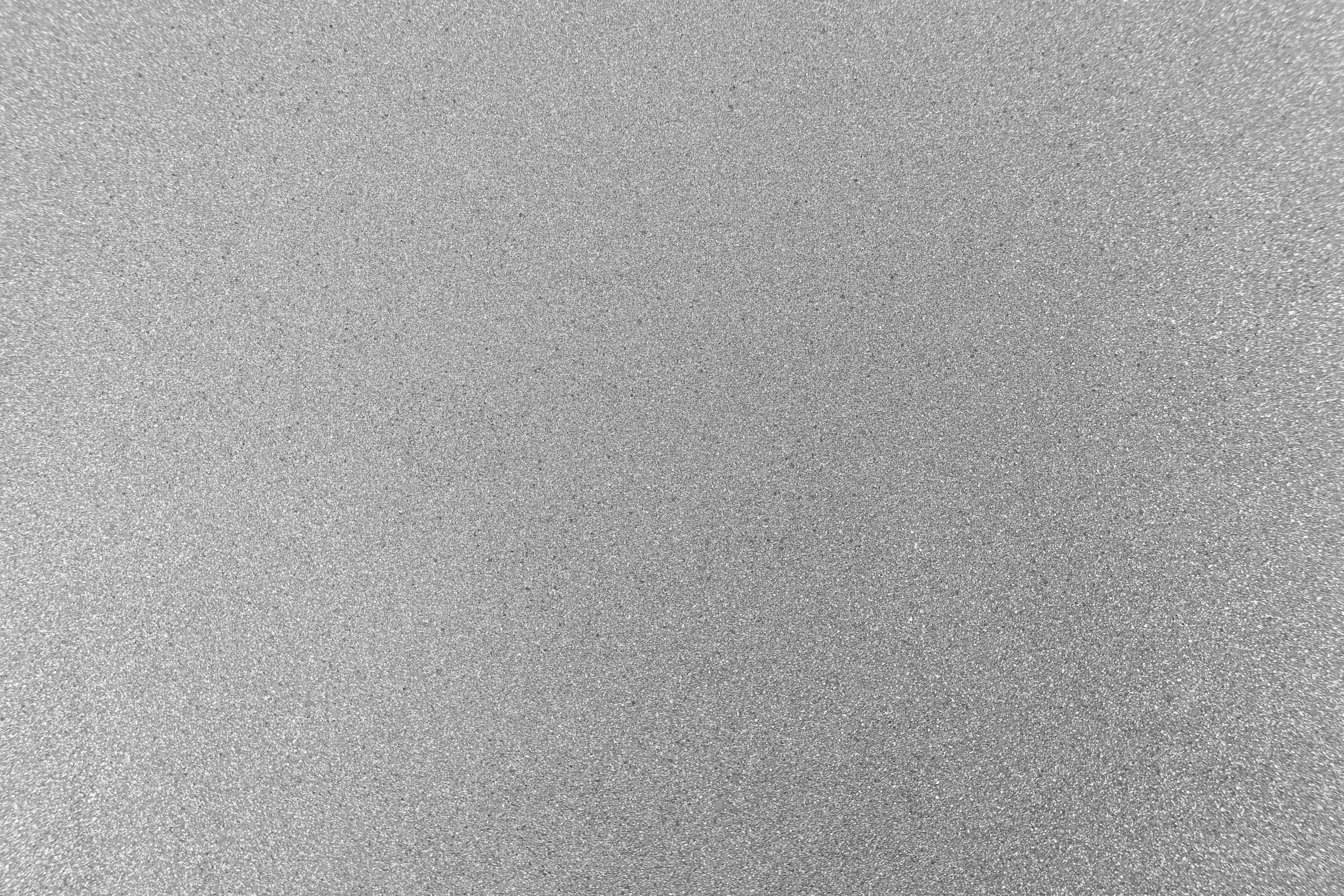 A textured grey surface, likely a close-up of a metallic or concrete material.
