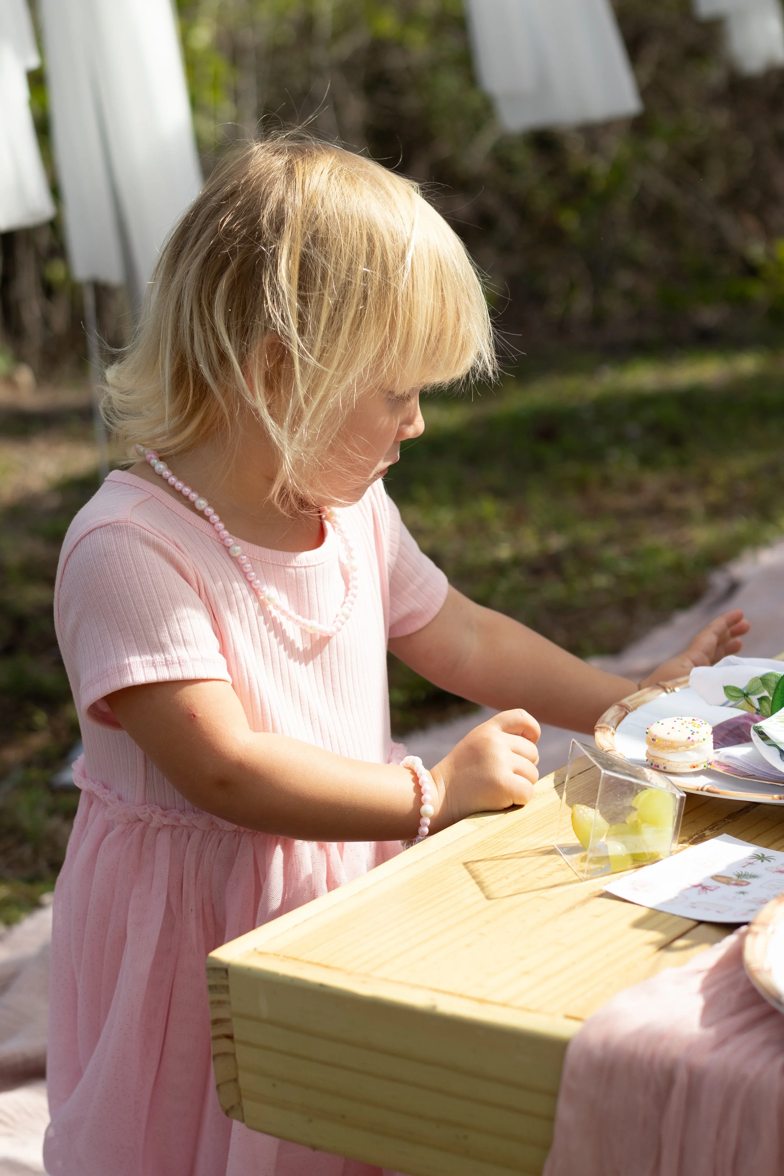 Little girl in pink dress sitting at tea party table