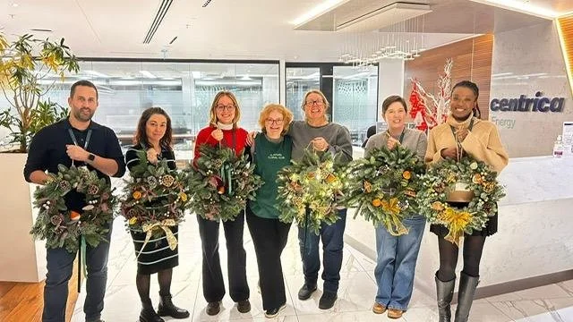 People at a Christmas Wreath workshop showing the wreaths they ma