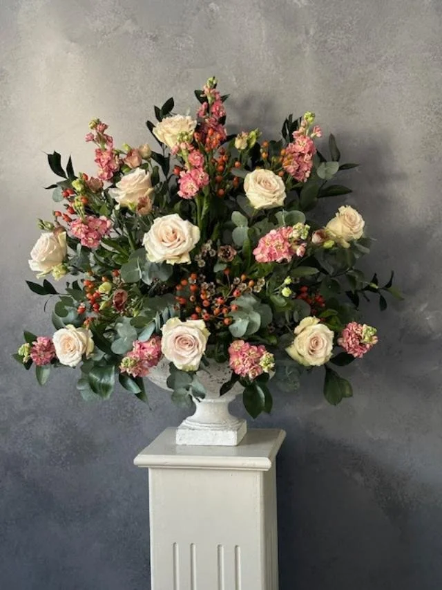 A church pedelstal arrangement with Roses and pink Stocks