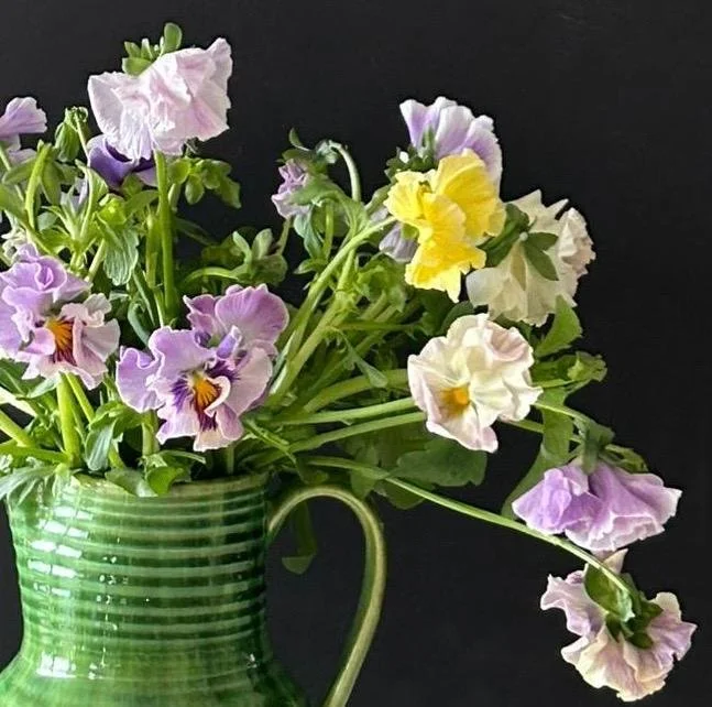 Lilac pansies in a green jug