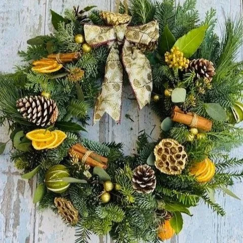 CHristmas wreath with oranges, limes, lotus heads and pine cones with a gold bow