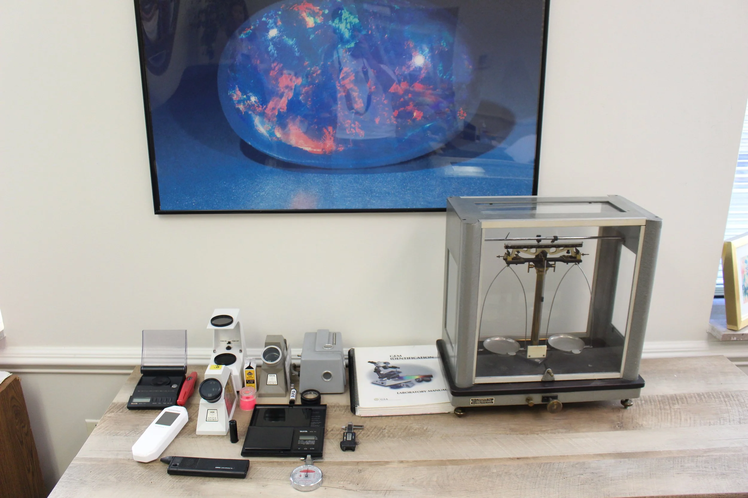 Collection of scientific instruments and devices on a wooden table in front of a large screen showing a space-themed image.